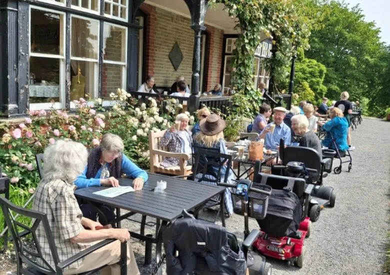 Photo of the group taking lunch at tables on the verandah